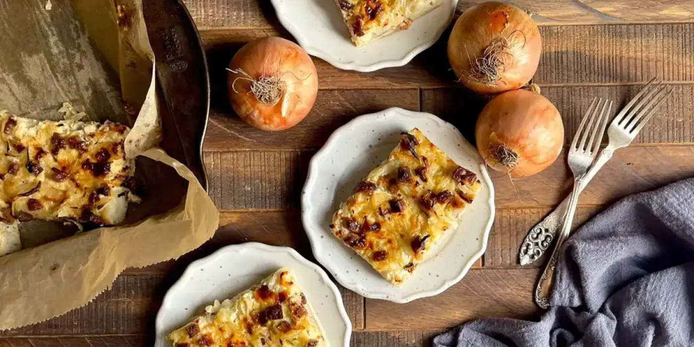 Herzhafter Zwiebelkuchen mit Räuchertofu auf rustikalem Holztisch angerichtet