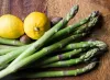 Frischer grüner Spargel mit Zitronen auf einem Holzbrett