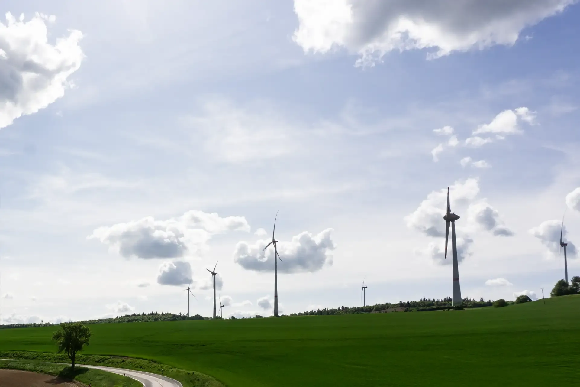 Windräder auf grünen Feldern nahe dem Schneebergerhof unter leicht bewölktem Himmel