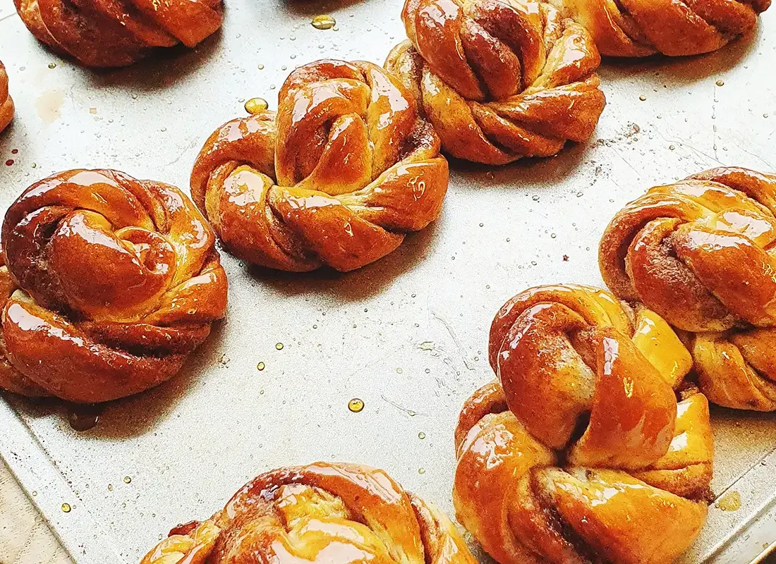 Glänzende Kardamom-Knoten frisch gebacken auf einem Backblech