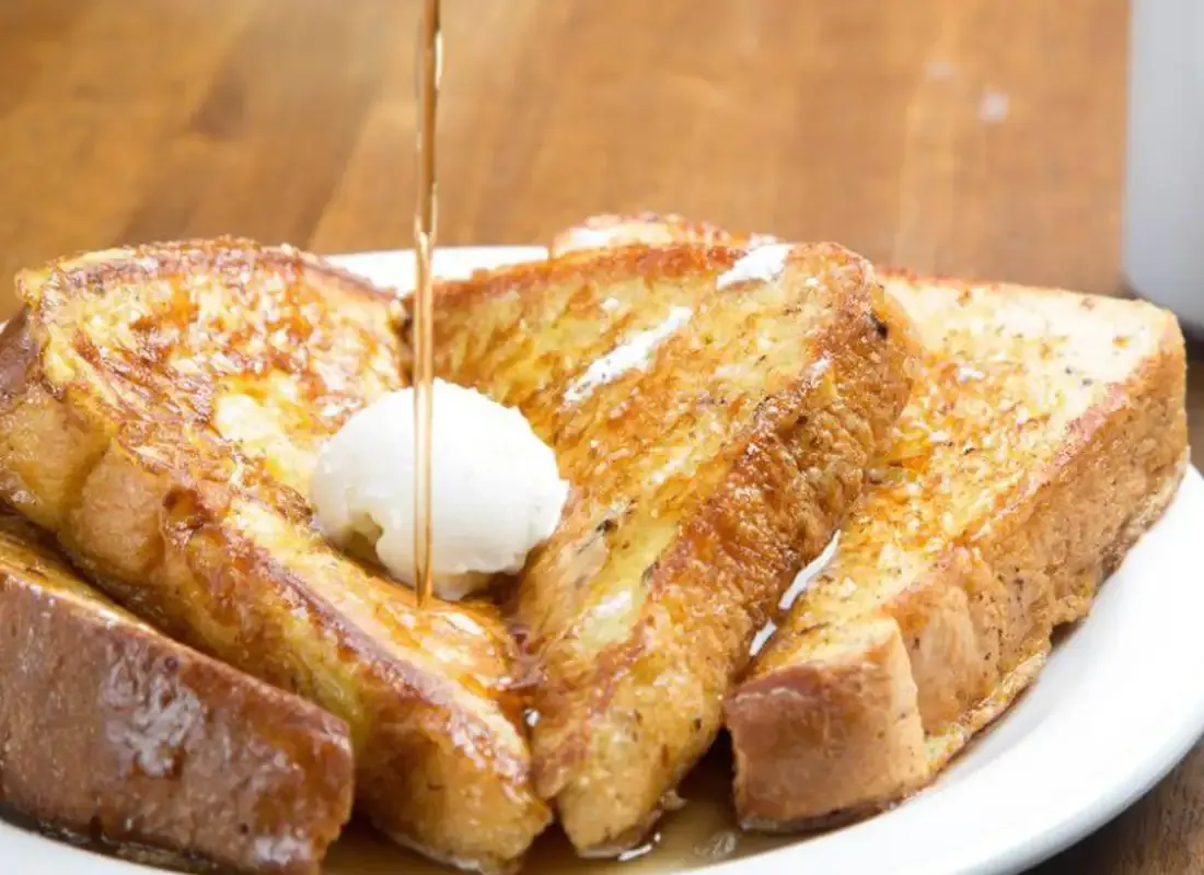 French Toast mit Ahornsirup und einem Klecks Butter auf einem weißen Teller