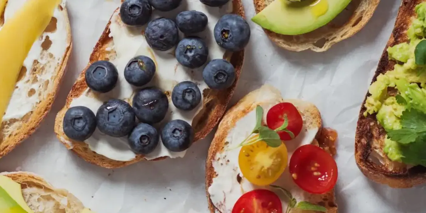 Bunte Auswahl belegter Brote mit frischem Obst, Gemüse und Aufstrichen