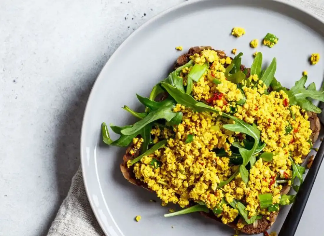 Vollkornbrot mit Rucola und Rührtofu auf einem grauen Teller