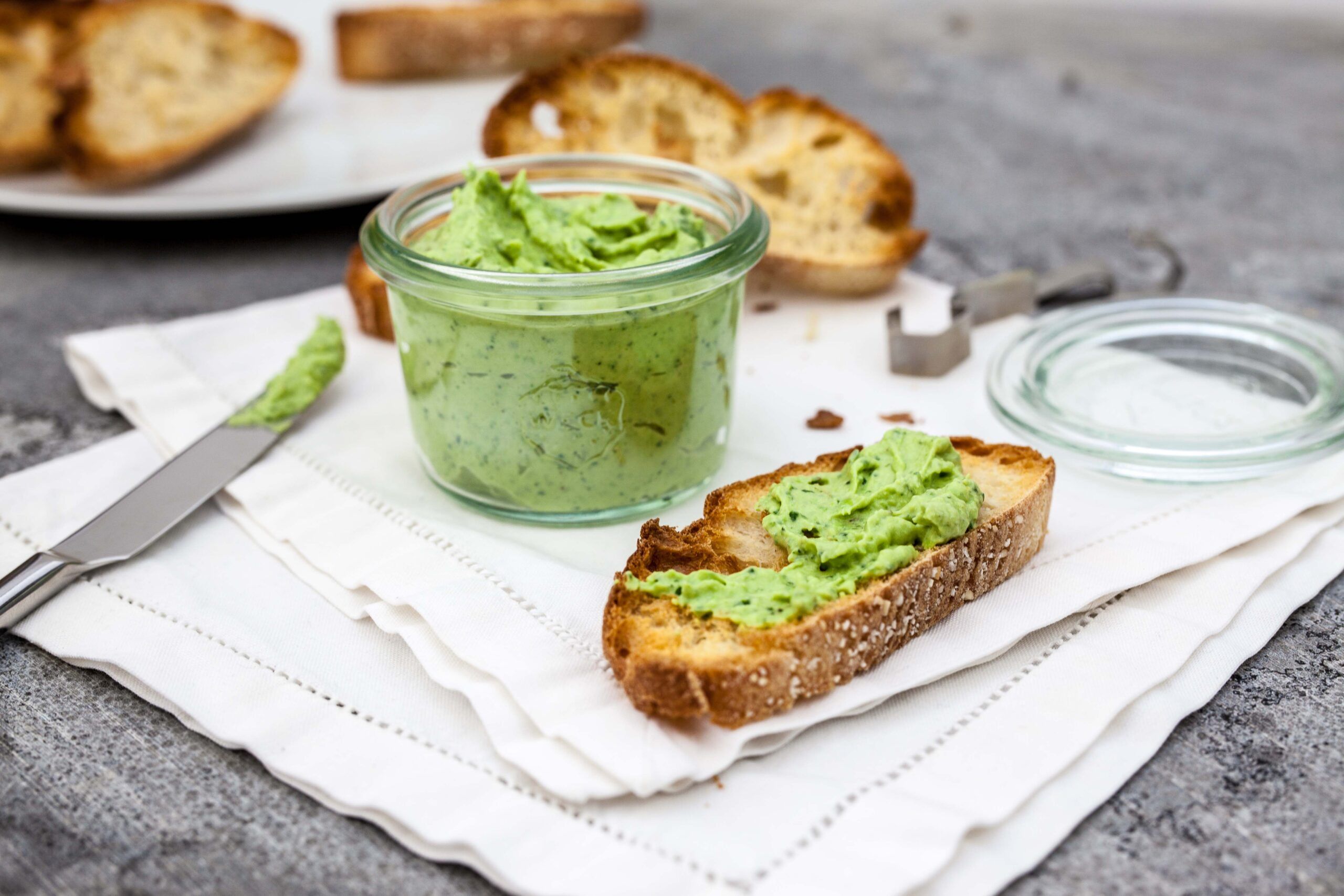 Frisches Brot mit selbstgemachter Bärlauchbutter und Glas auf hellem Frühstückstisch
