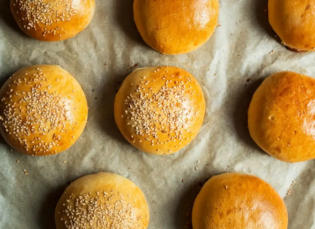 Frisch gebackene Burger Buns mit Sesam auf Backpapier